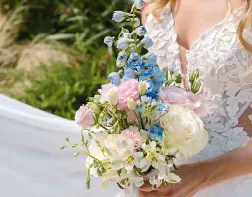 Eine Frau in einem weißen Brautkleid hält einen Blumenstrauß.
