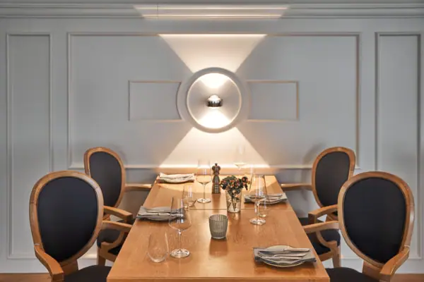 Ein Tisch mit vier Stühlen sowie Weingläsern und einer Vase darauf.