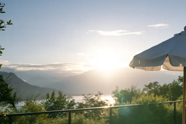 Weißer Sonnenschirm auf einem Deck mit Blick auf einen Zaun und ein Gewässer im Hintergrund