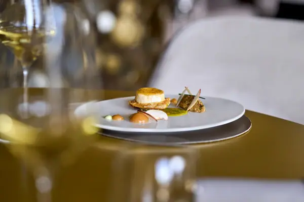 Restaurant Ein Teller mit Essen auf einem Tisch, daneben ein Weinglas.