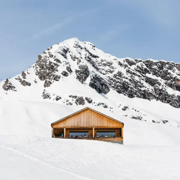 A building covered in snow at a ski resort with surrounding snowy landscape.