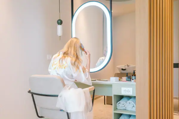 Eine Frau im Bademantel kämmt ihr Haar vor einem Spiegel.