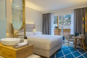 Schlafbereich mit offenem Bad Schlafzimmer mit großem Bett, Stuhl und großem Spiegel.