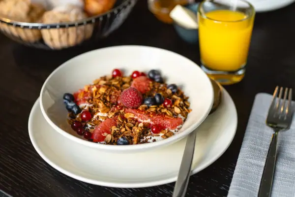 Joghurt Eine Schale mit Obst und Müsli neben einem Glas Saft.