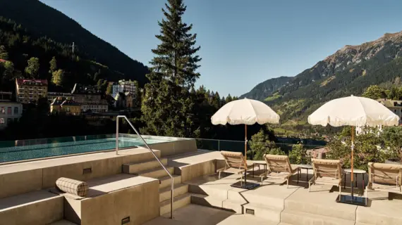 Sonnenterrasse mit Infinity-Pool und Liegestühlen im Straubinger Grand Hotel in Bad Gastein, umgeben von alpiner Bergkulisse und Blick über das Gasteinertal.