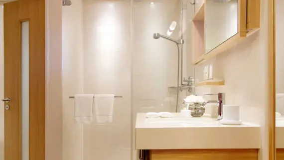 A bright bathroom with a shower and washbasin.