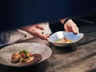 Koch hält einen Teller mit Essen.