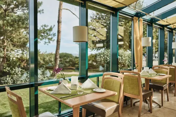 Ein Tisch mit Stühlen und Servietten in einem Raum mit Fenstern.