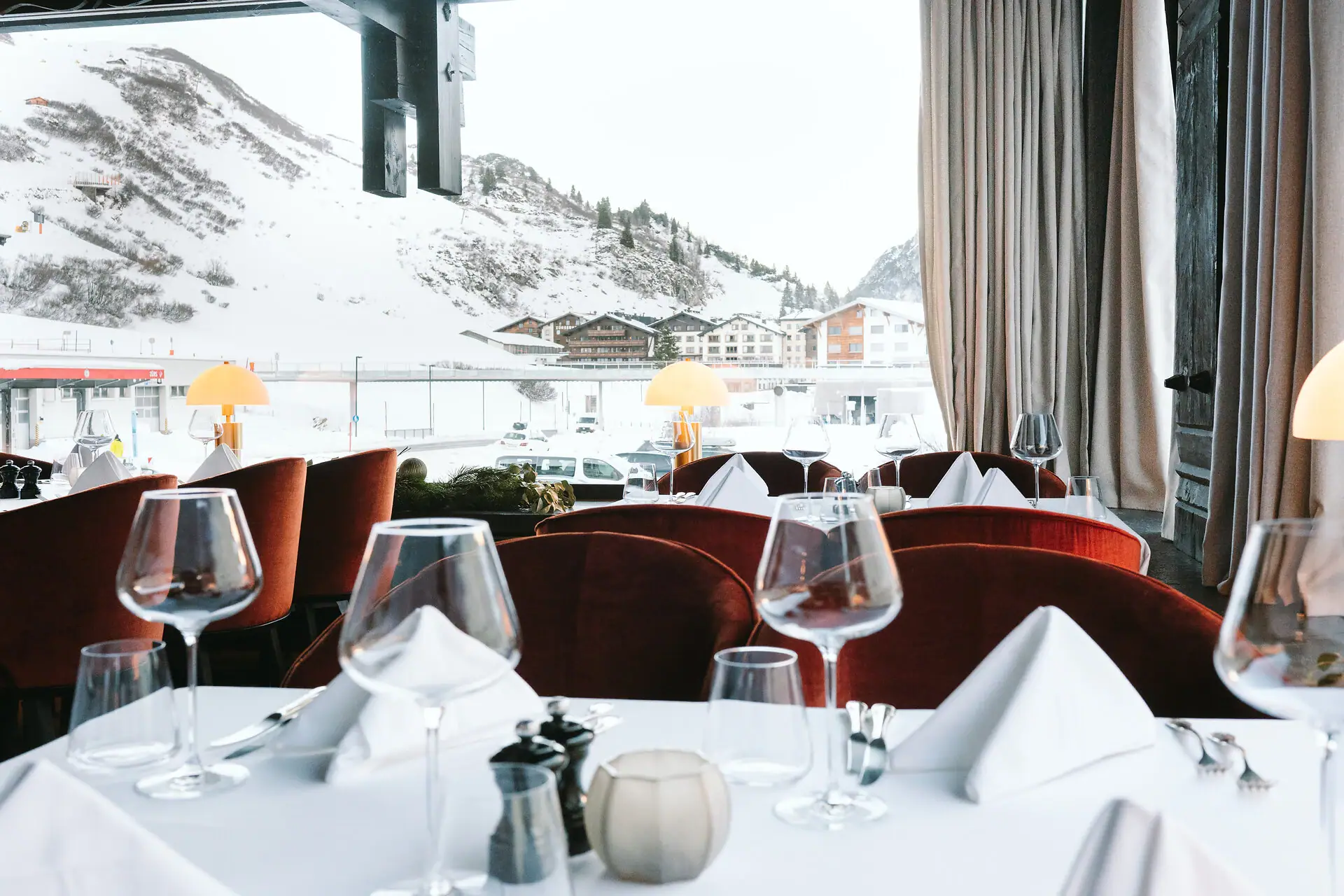 Ein festlich gedeckter Tisch mit Weingläsern vor einer schneebedeckten Bergkulisse.