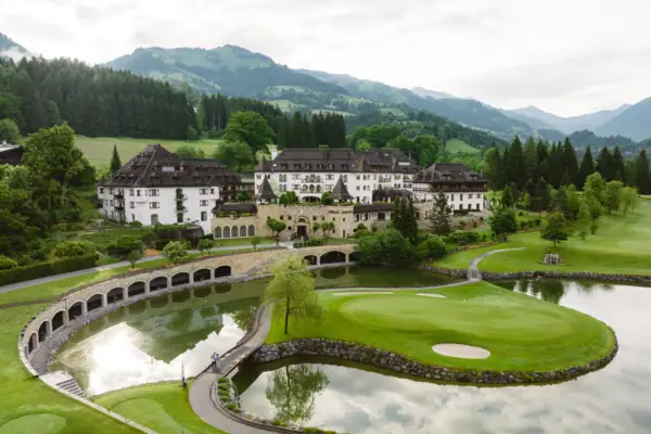 Golfplatz mit dem Schlosshotel Kitzbühel und Bergen im Hintergrund.
