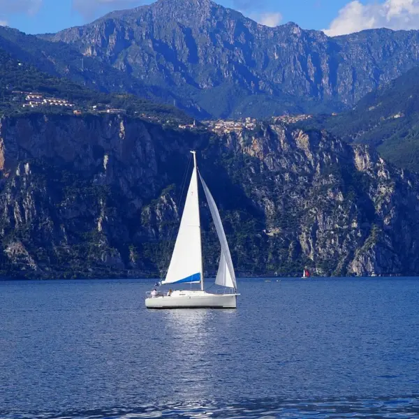 Segelboot auf dem Wasser mit Bergen im Hintergrund.