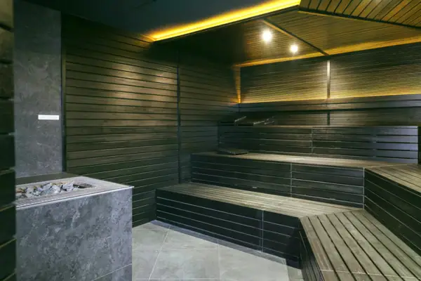 Dunkle finnische Sauna mit Holzbänken und Saunaofen im A-ROSA Gardasee.