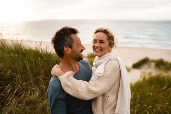 Mann und Frau umarmen sich am Strand.