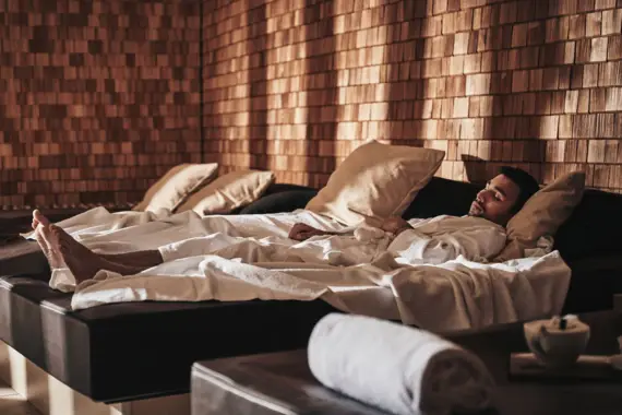 Ein Mann liegt auf einer Liege im SPA Bereich und schläft.