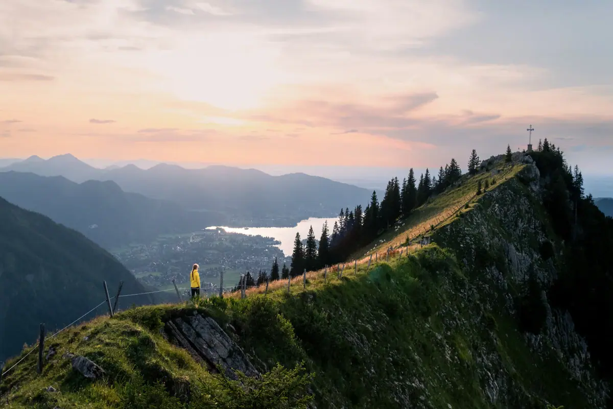 Eine Person steht auf einem Berggipfel bei einer Wanderung am Tegernsee.