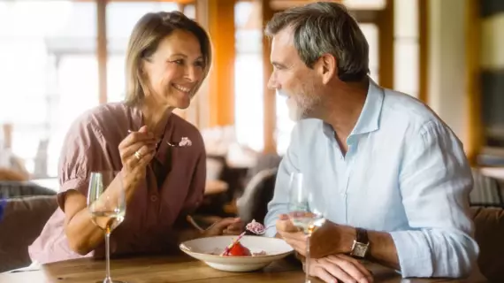 Ein Paar teilt sich bei einem Glas Wein in einem Restaurant mit warmer Atmosphäre ein Eis. 