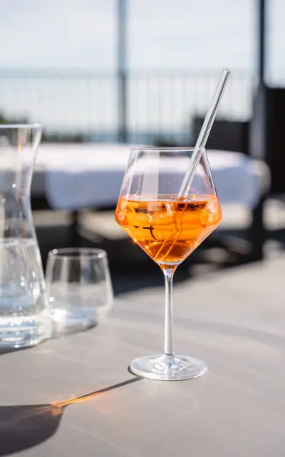 Ein Glas mit orangefarbener Flüssigkeit und Eis auf einem Tisch.