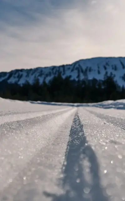 Schneebedeckter Boden mit Skispuren und Berglandschaft im Hintergrund.