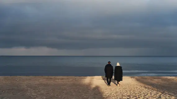 Ein Mann und eine Frau laufen am Strand entlang. 