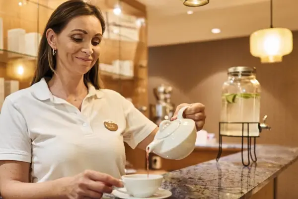 Eine Frau gießt Tee in eine Tasse ein.