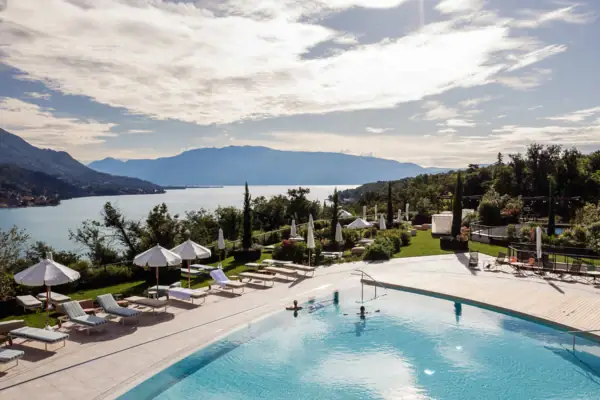 Ein Pool mit Liegestühlen und Sonnenschirmen am Wasser.