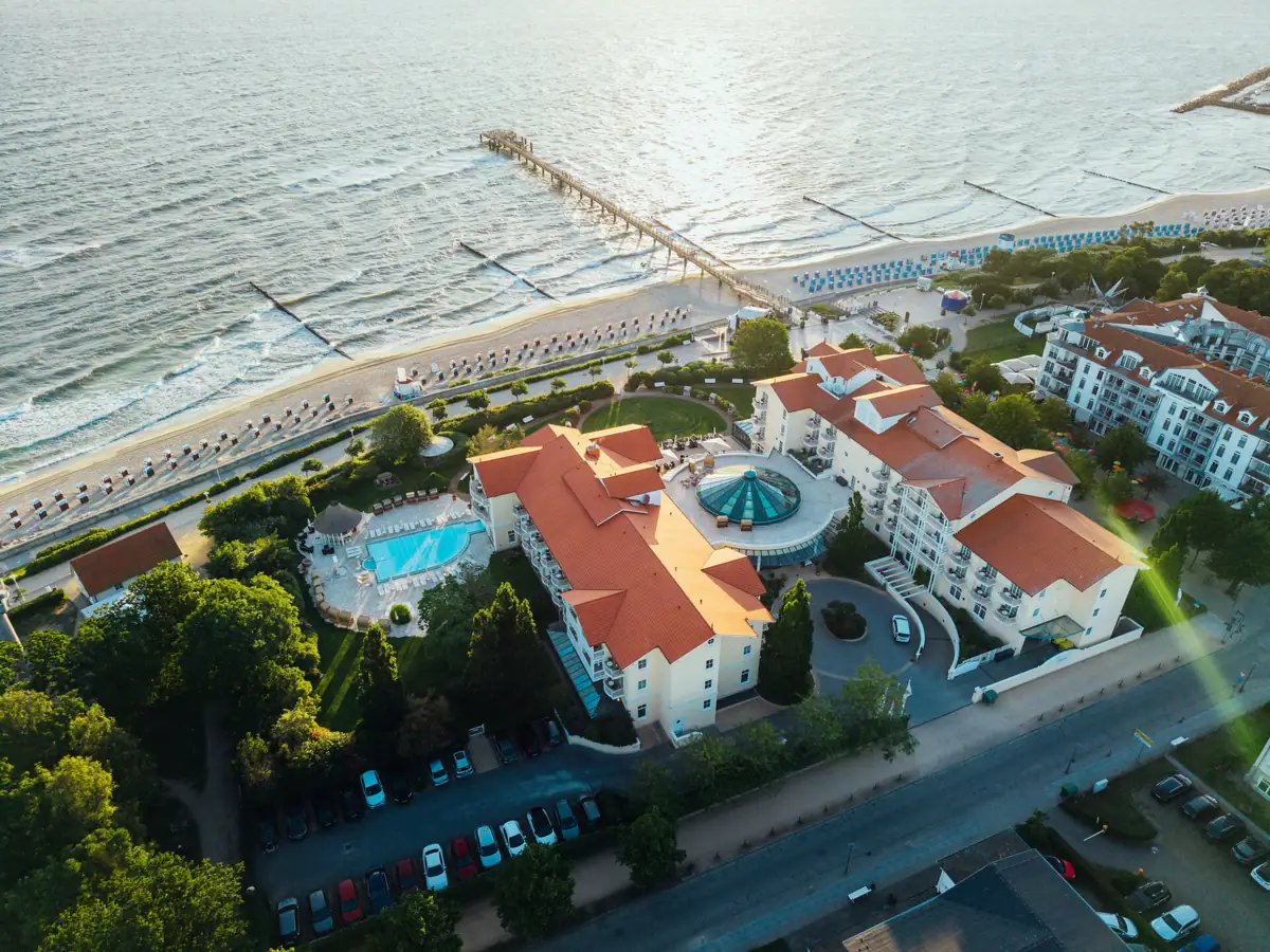 Luftaufnahme eines Resorts mit Pool und Steg, umgeben von Bäumen und Wasser.