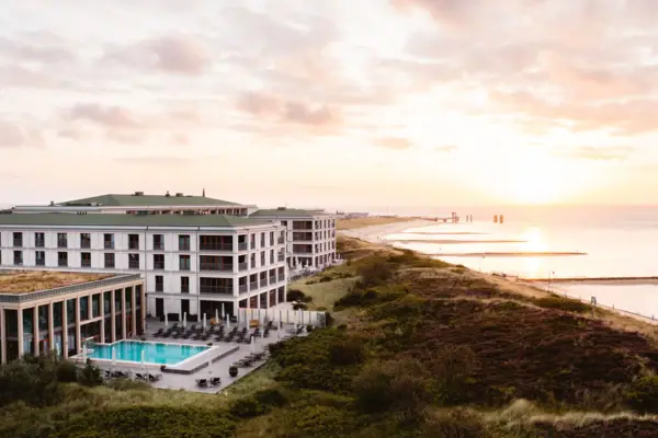 Das A-ROSA Sylt mit Pool umgeben von Dünen und mit Blick auf die Nordsee.