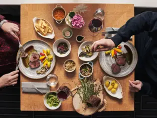 Gruppe von Personen beim Essen an einem Tisch mit verschiedenen Speisen aus der Vogelperspektive..