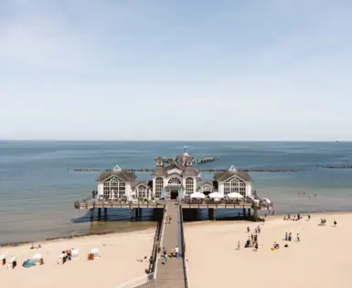 Strand mit einem Gebäude auf dem Wasser, umgeben von blauem Himmel und Wolken.