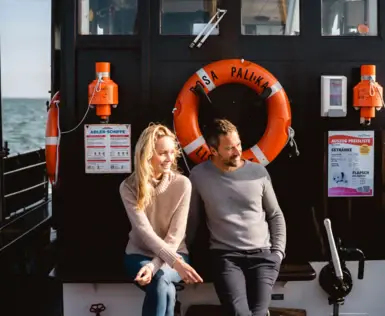 Ein Mann und eine Frau sitzen in Jeanskleidung auf einem Boot.