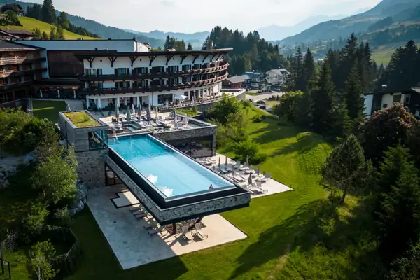 A-ROSA Ifen Hotel Kleinwalsertal Außenpool eines Hotels mit Blick auf Bäume und Himmel.
