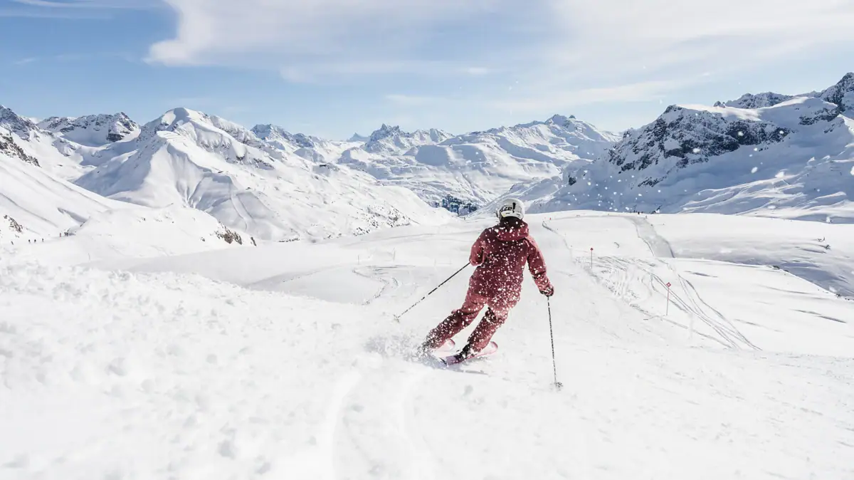 Eine Person fährt auf Skiern einen schneebedeckten Berg hinunter.