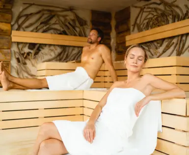 Ein Mann und eine Frau sitzen auf einer Bank in einer Sauna.