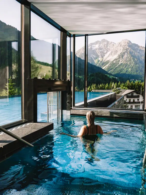 Eine Frau in einem Pool mit Bergen im Hintergrund.