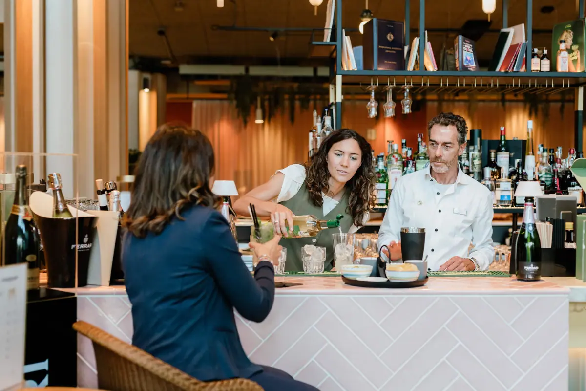 Eine Frau schenkt einer anderen Frau an einer Bar ein Getränk ein.
