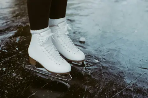 Two feet with skates are standing on a patch of ice.