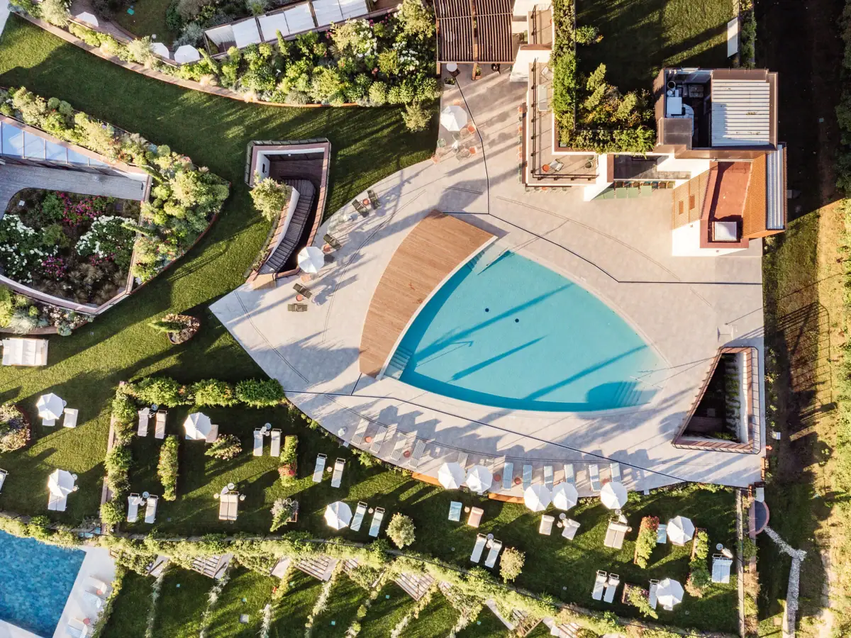 Das Schwimmbecken des Gartenpools aus der Luft aufgenommen, umgeben von Gras und Rasenflächen.