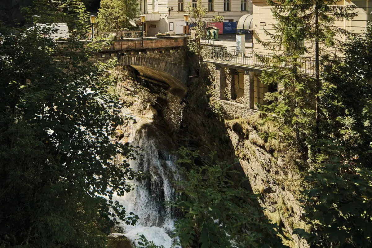 Eine Brücke über eine Klippe mit Wasserfall.
