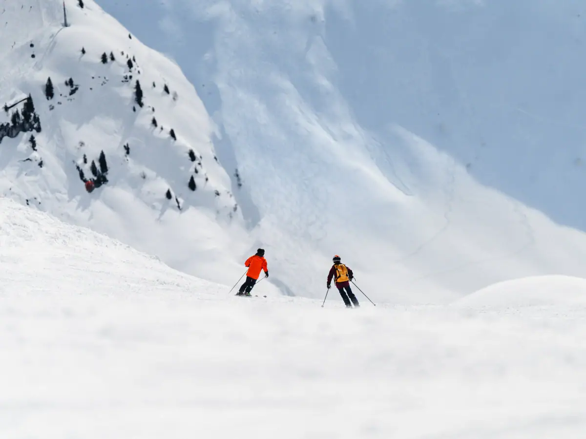 Eine Gruppe von Menschen fährt auf Skiern einen schneebedeckten Berg hinunter.
