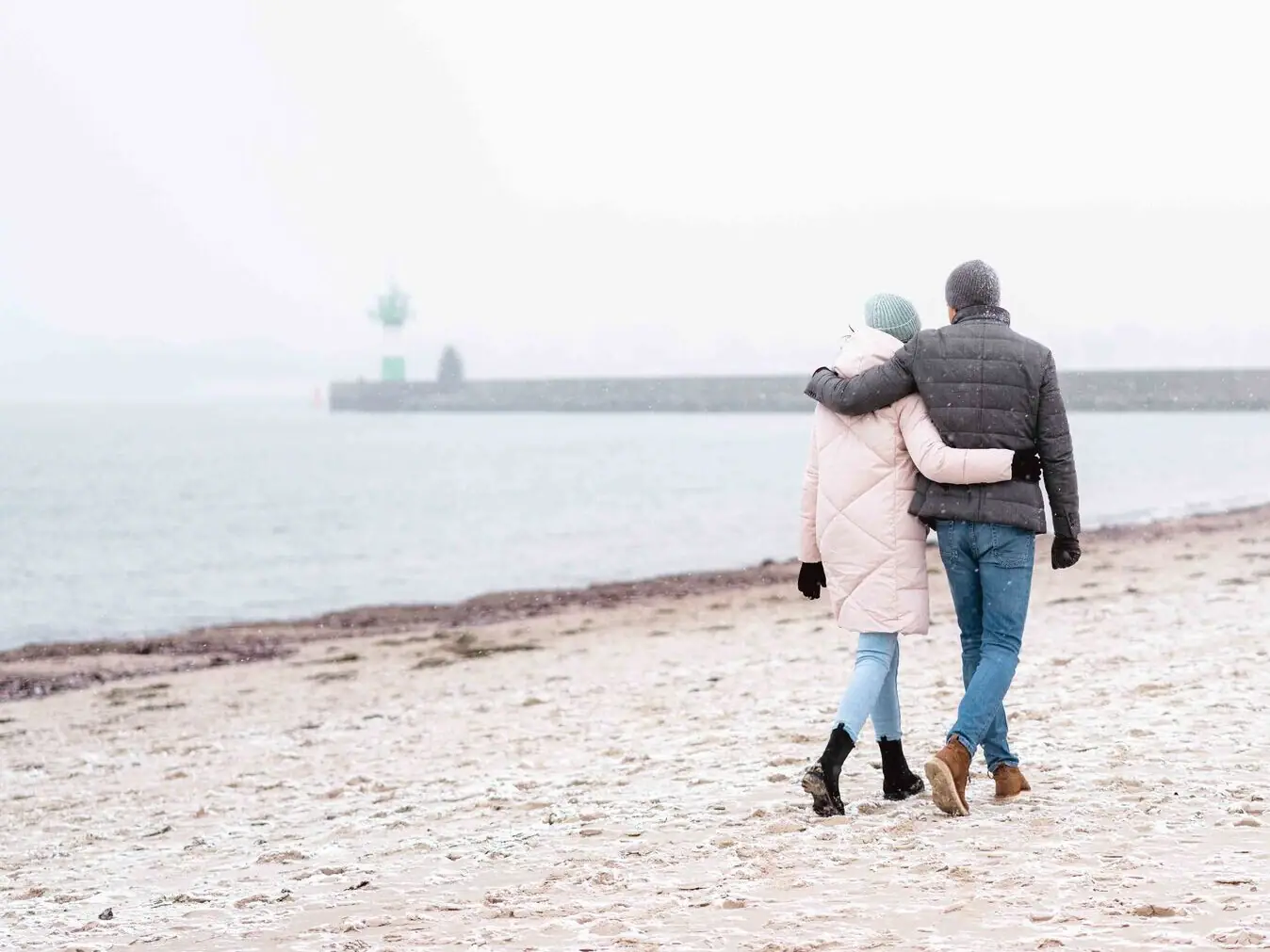 Ein Mann und eine Frau gehen am Strand entlang.