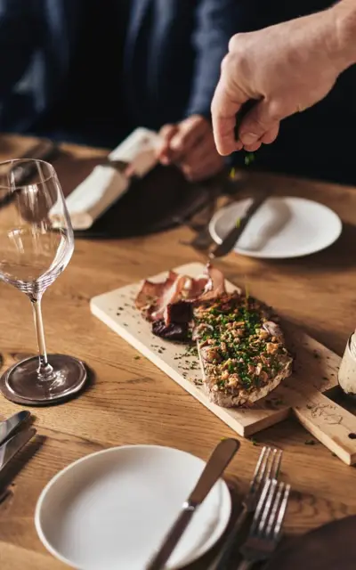 Person scattering greens on a wooden board in a kitchen.