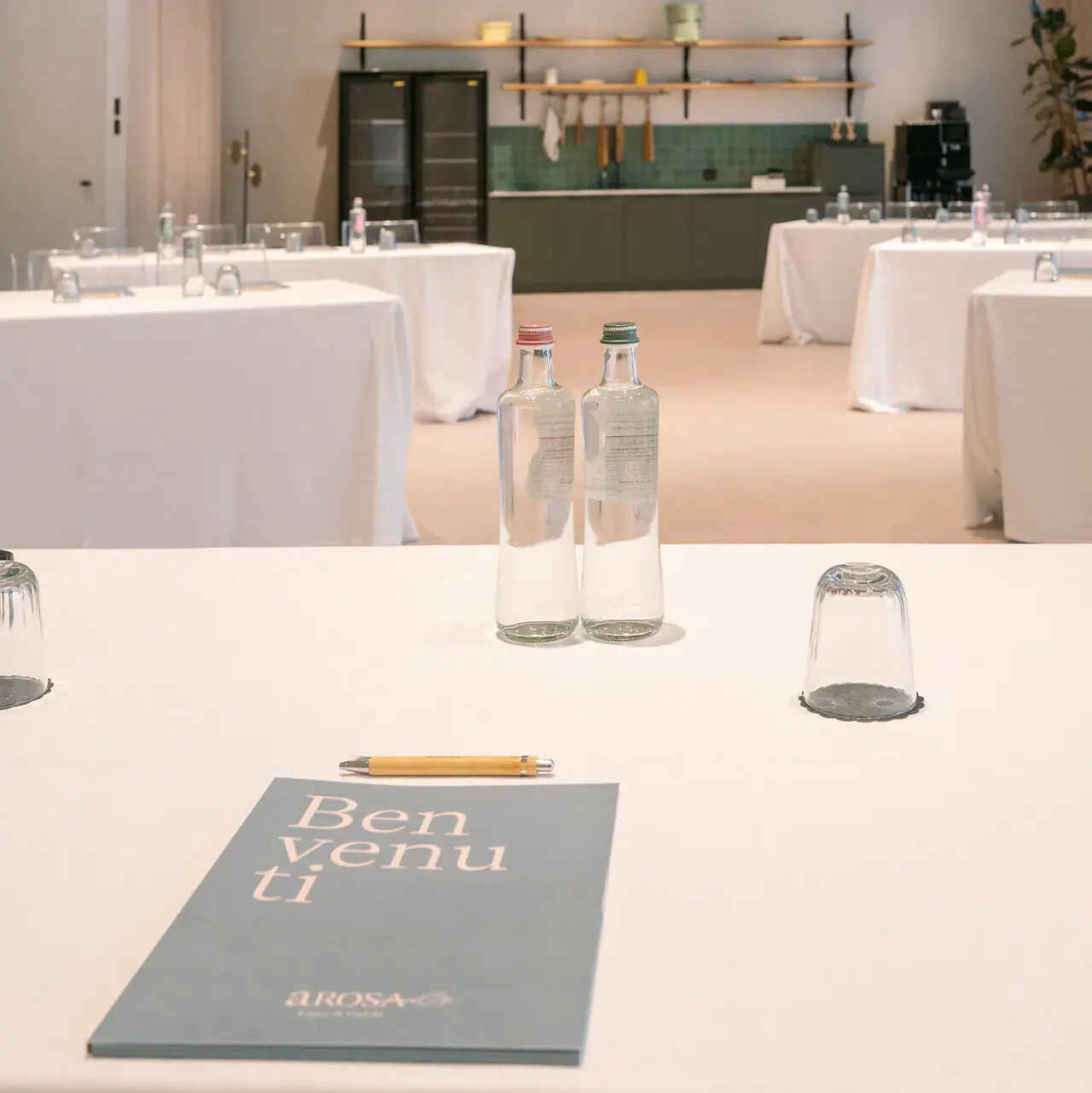 Ein Tisch mit weißem Tischtuch, Wasserflaschen und Vasen.
