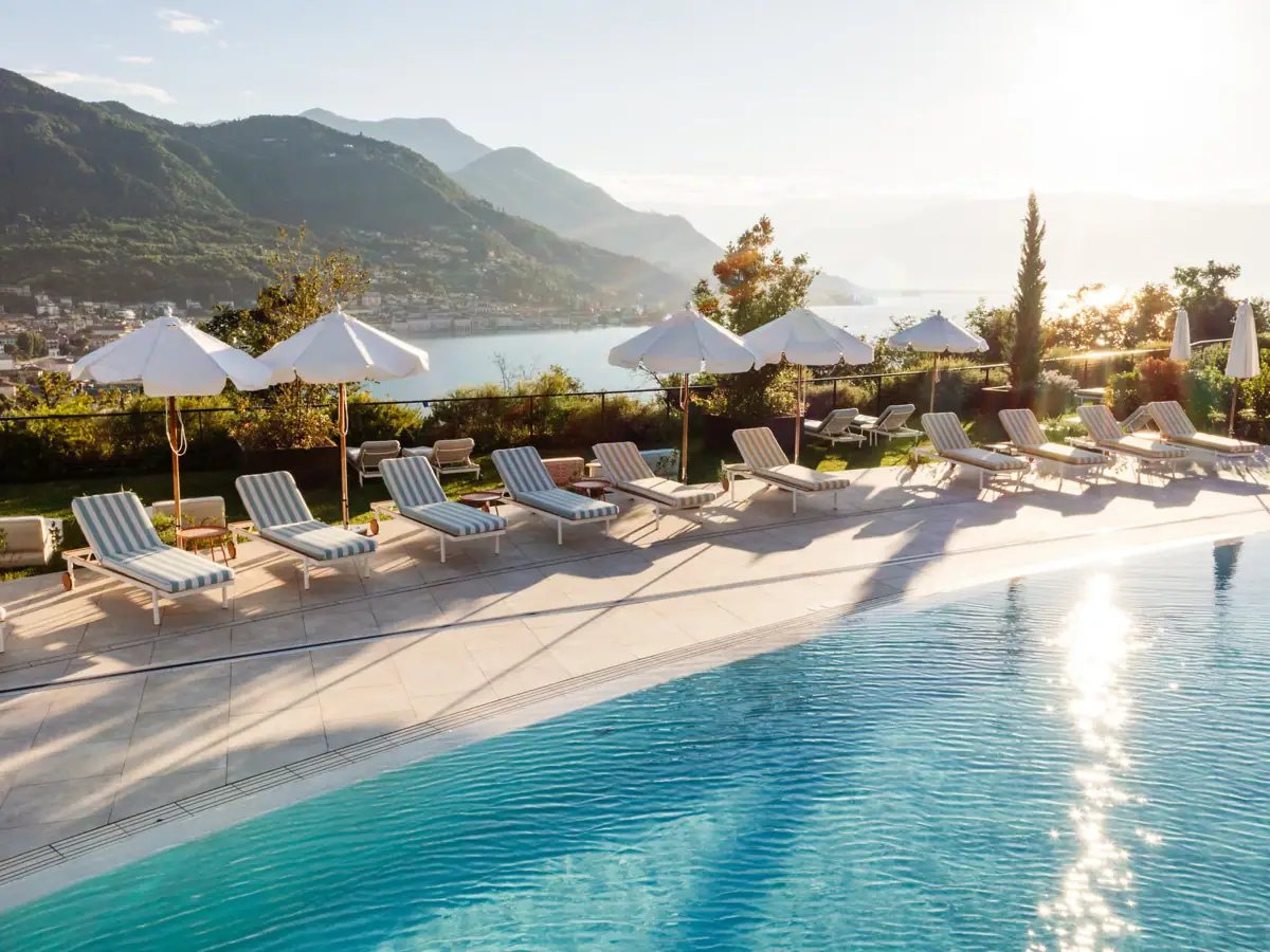 Ein Pool mit Liegestühlen und Sonnenschirmen am Wasser.