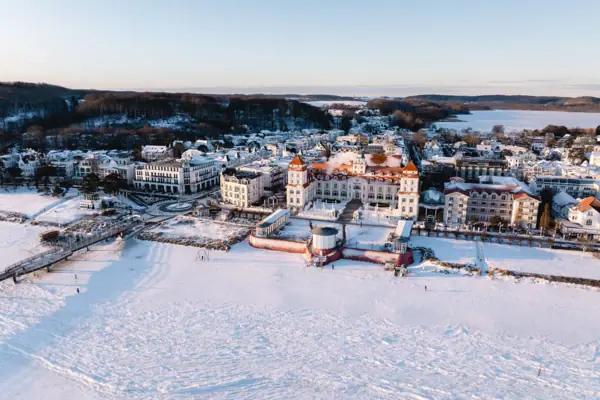 Schneebedeckte Stadt mit Gebäuden und einem Gewässer im Winter.