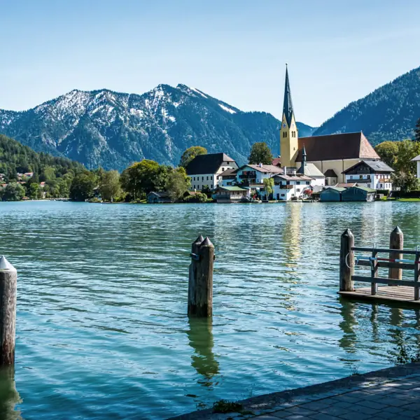 Ein See mit einer Kirche und Bergen im Hintergrund.