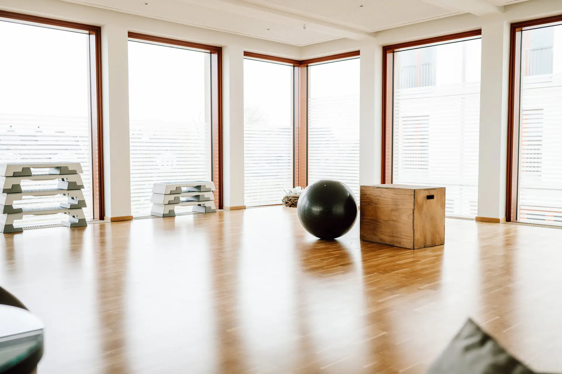 Großer schwarzer Ball auf einem Holzboden in einem Raum mit Fenstern.