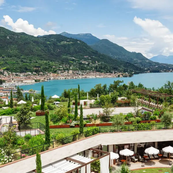 Das A-ROSA mit Garten und Gardasee im Hintergrund der Berge.