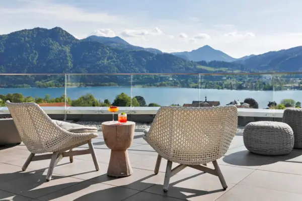 Ein Tisch und Stühle auf einer Terrasse mit Blick auf einen See.