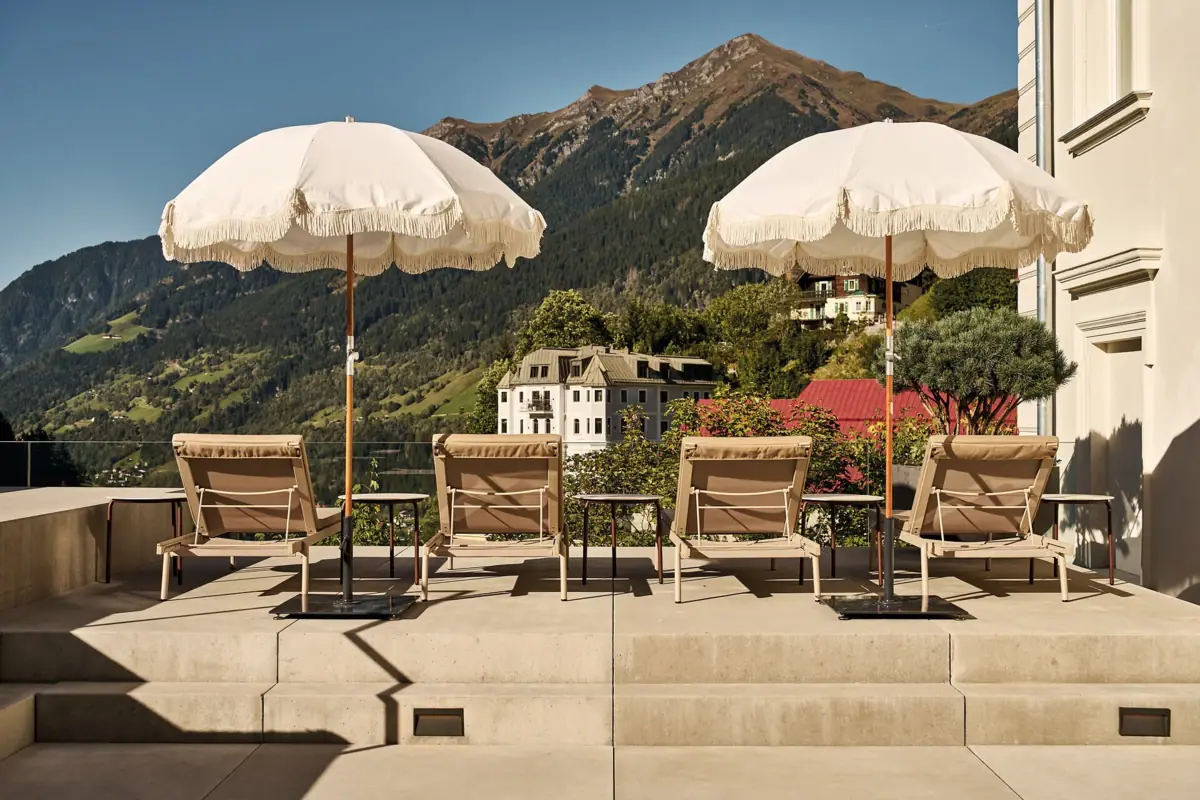 Eine Gruppe von Stühlen und Sonnenschirmen auf einer Terrasse.