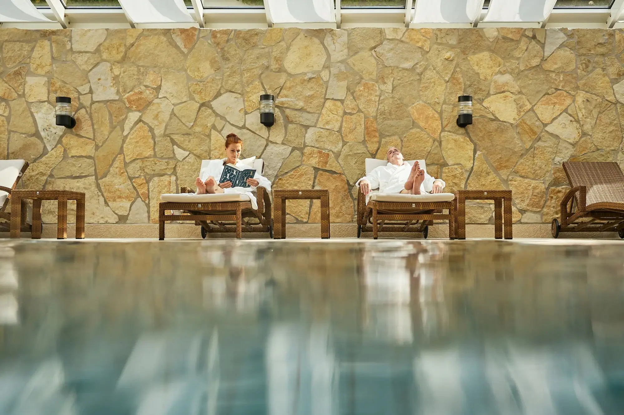 Ein Mann und eine Frau sitzen auf Stühlen am Pool.